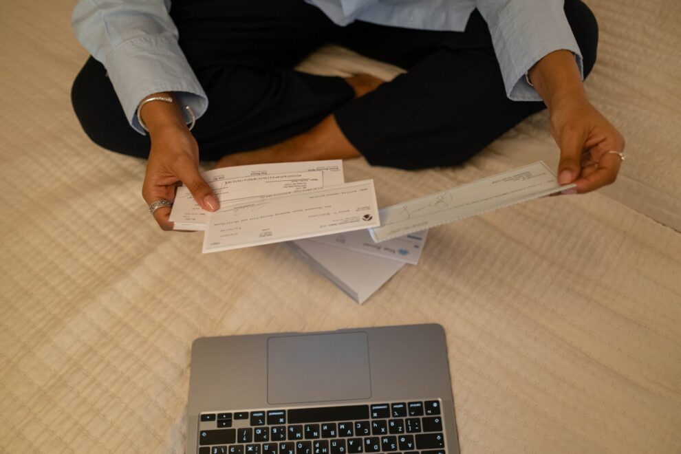 Woman sitting on a bed going through her utilities costs and bills